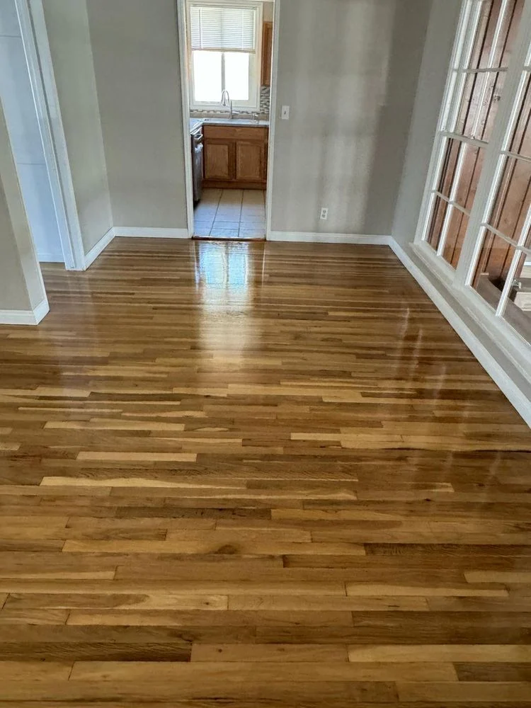 Living room with natural hardwood flooring, sunlight reflecting on the surface, emphasizing classic, warm tones and smooth finish.