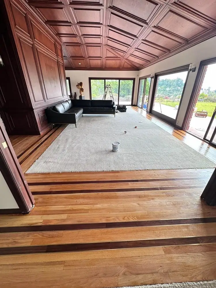 Solid hardwood flooring refinished with a natural wood tone in living room with large windows