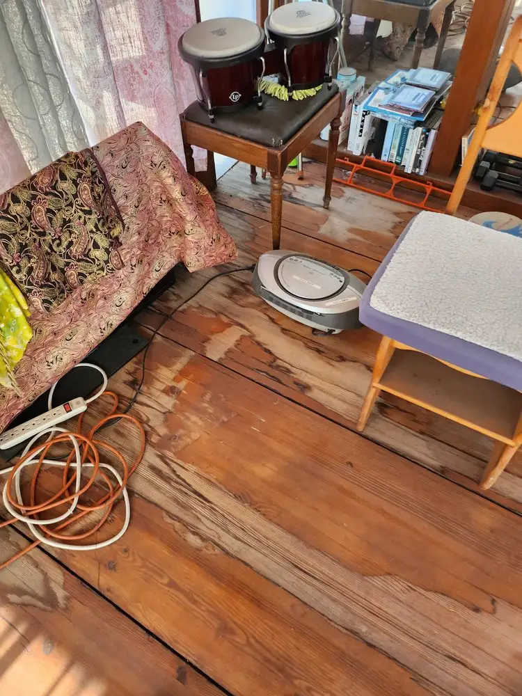 Original wooden floor boards showing wear and uneven surfaces before refinishing