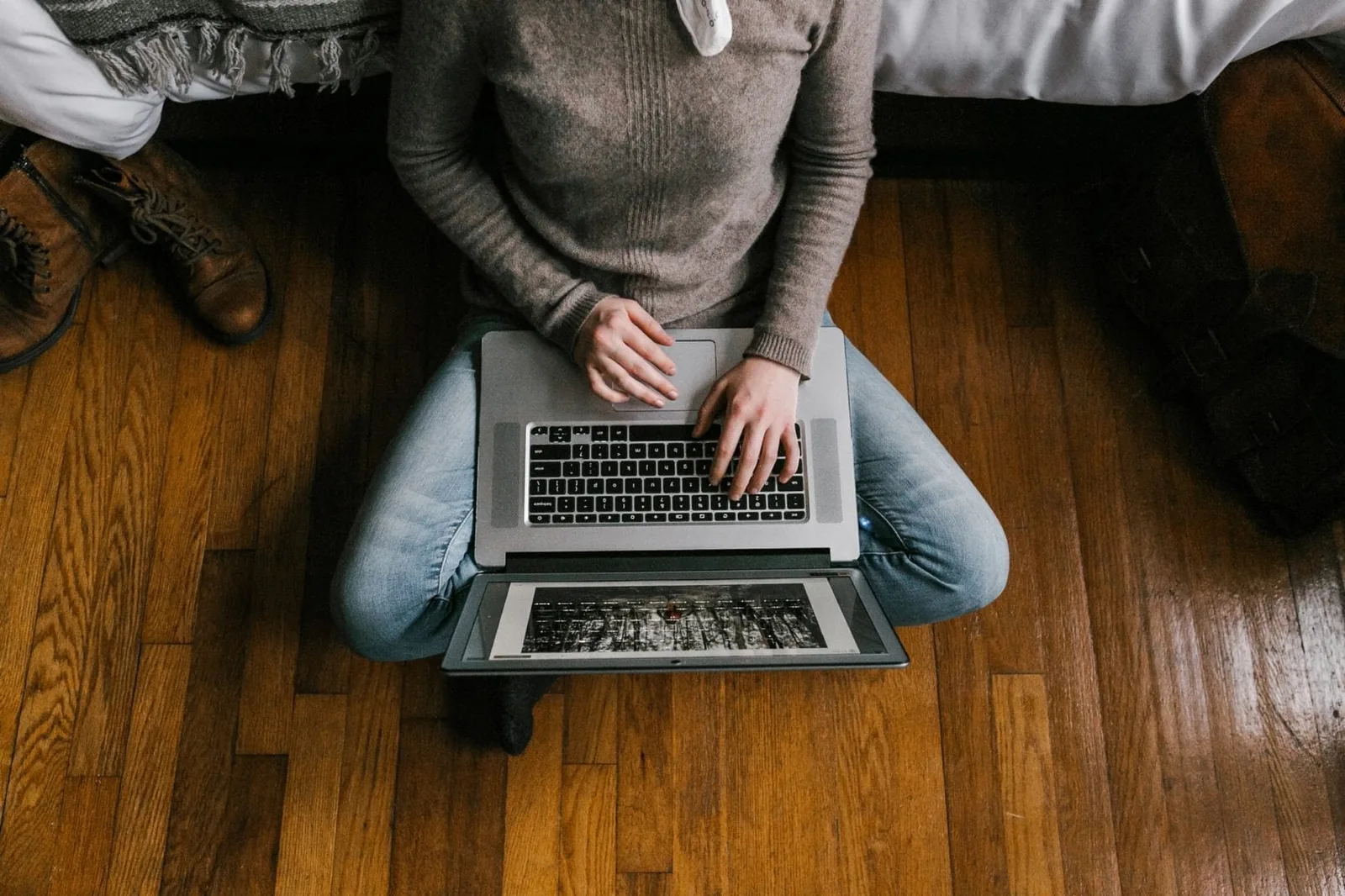 Person sitting on a hardwood floor working on a laptop Person sitting on a hardwood floor working on a laptop